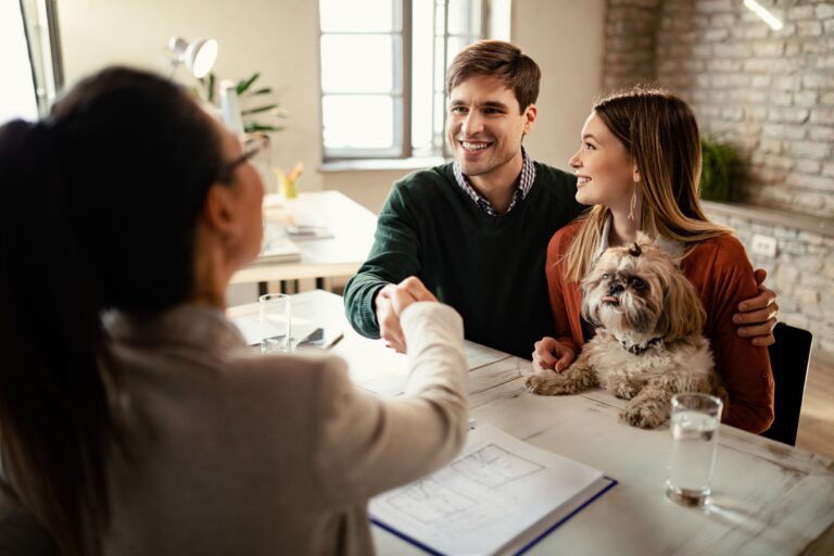Жилищното кредитиране през август 2025 happy couple with dog shaking hands with real estate agent office1